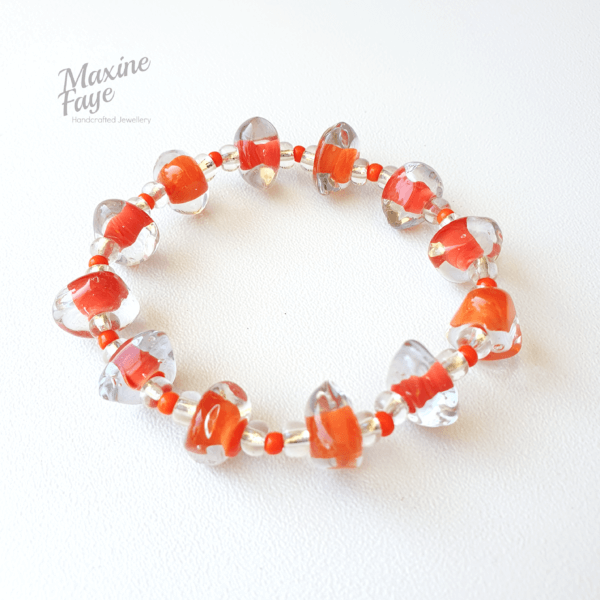 Chunky triangular nuggets of clear glass have a core of Tangerine orange and are separated by a pattern of silver-lined and orange glass spacer beads in this stretch style bracelet