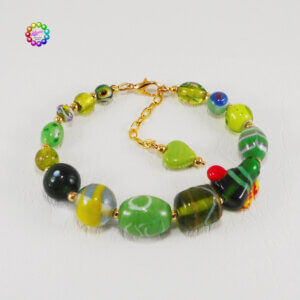 A fabulous mix of glass beads in various shades of green are highlighted with splashes of red, yellow and blues – all the colours of a tropical island paradise in this lamp-work glass bracelet.